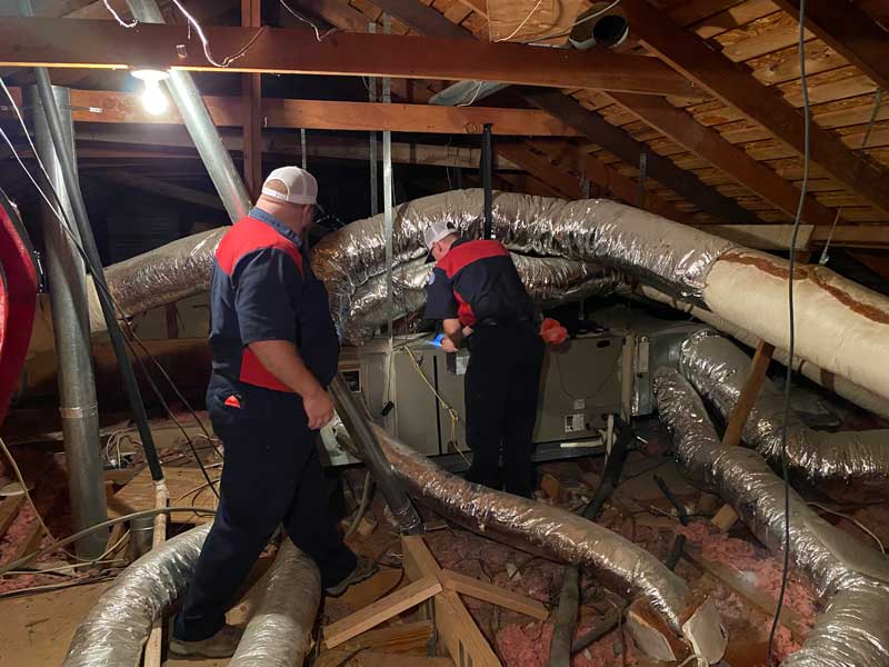 Two workers handling attic ductwork