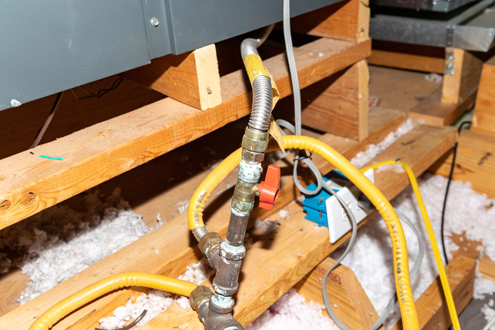 plumbing pipes and wiring in an attic with insulation