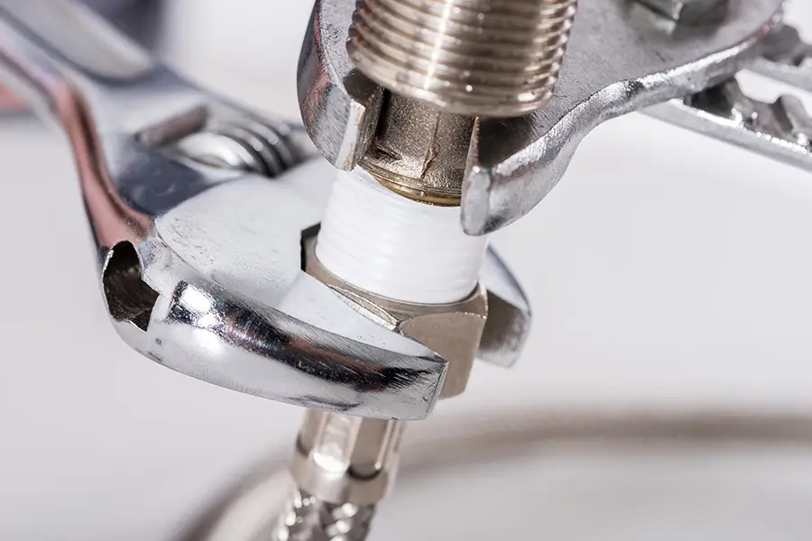 Close-up of a plumbing connection being tightened with wrenches